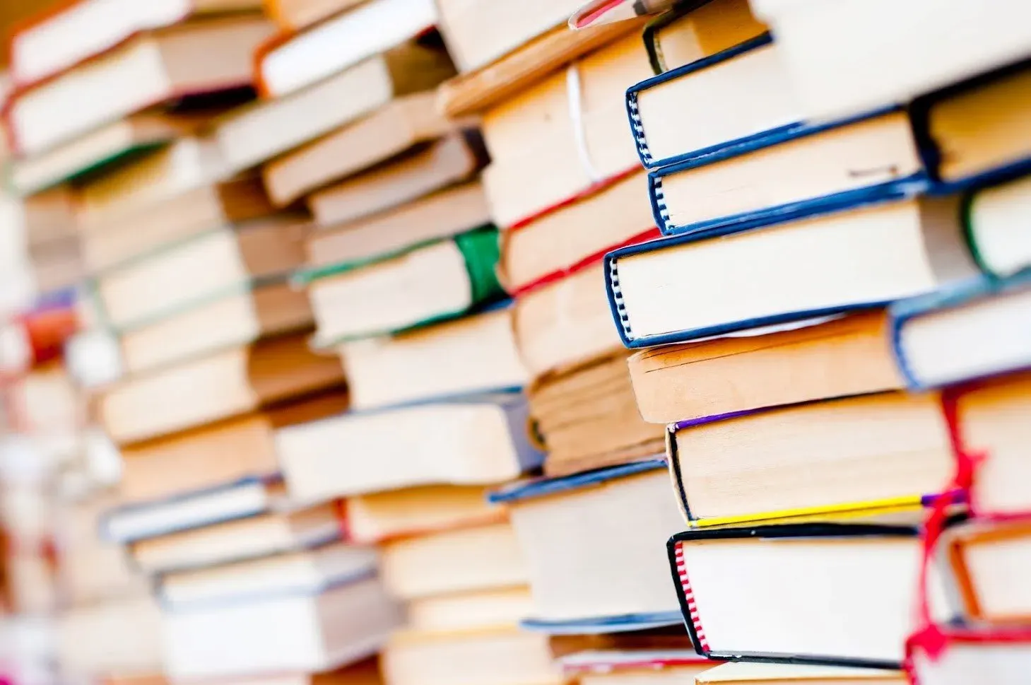 Piles of books, various colors, stacked high. Close-up view.