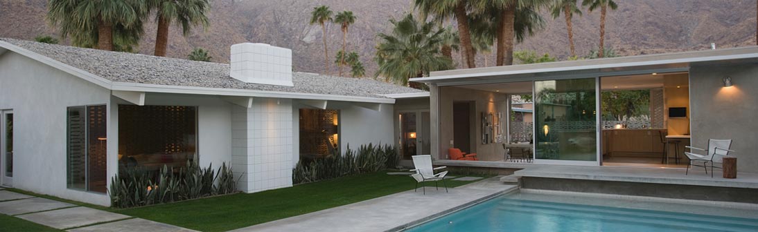 Modern white house with a pool, palm trees, and a mountain backdrop.