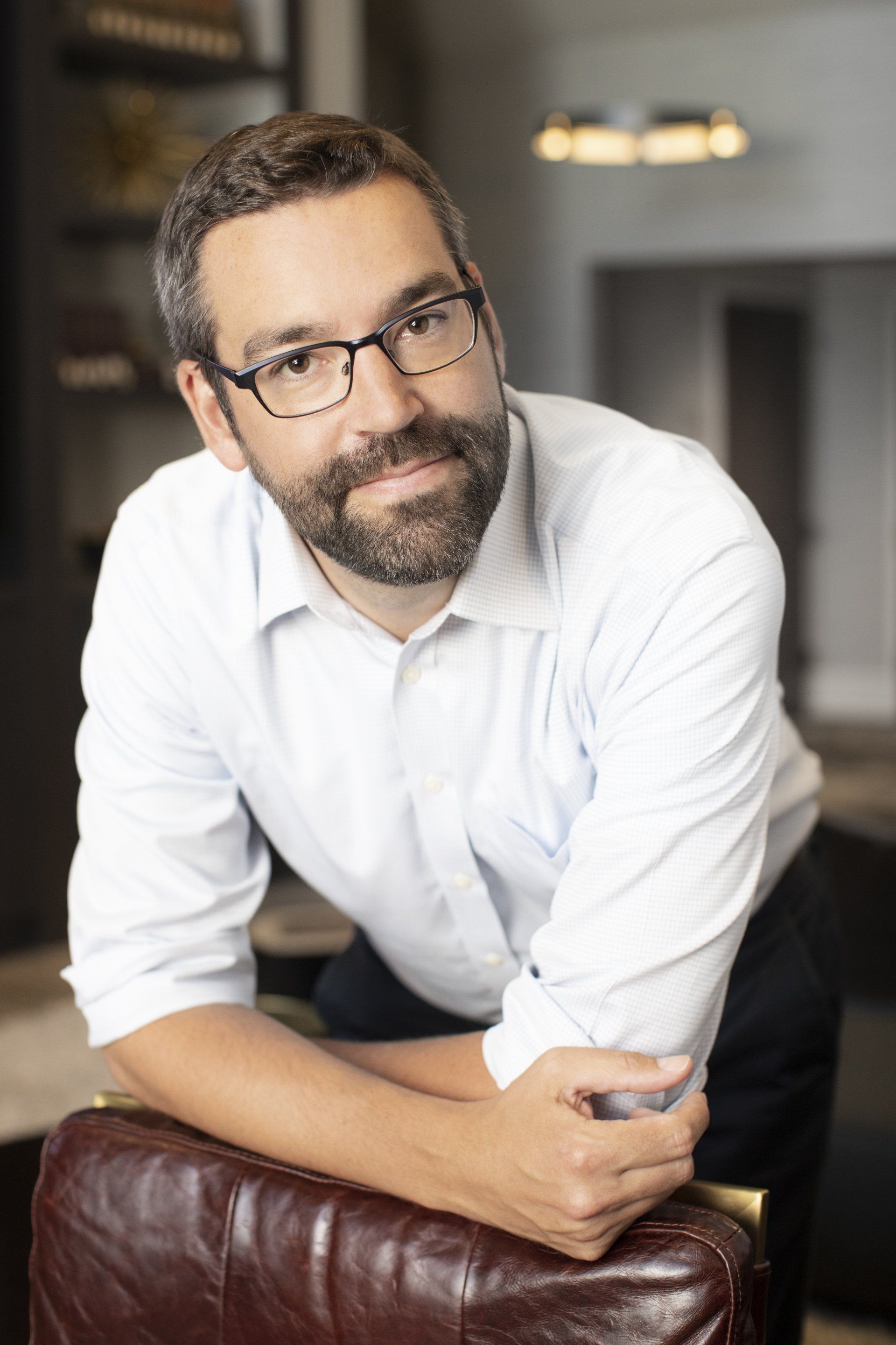 A man with a beard and glasses is sitting on a couch.