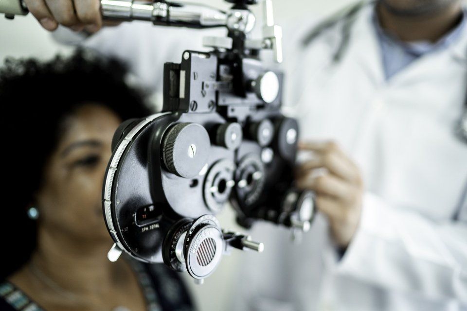 Una persona sottoposta a un esame della vista mediante un forottero da parte di un medico in un ambiente medico.