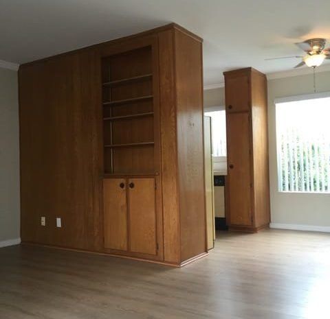 Living area with hardwood floors and wood paneling on walls