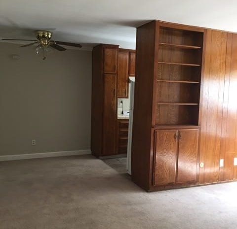 Carpeted living area and a ceiling fan over dining area