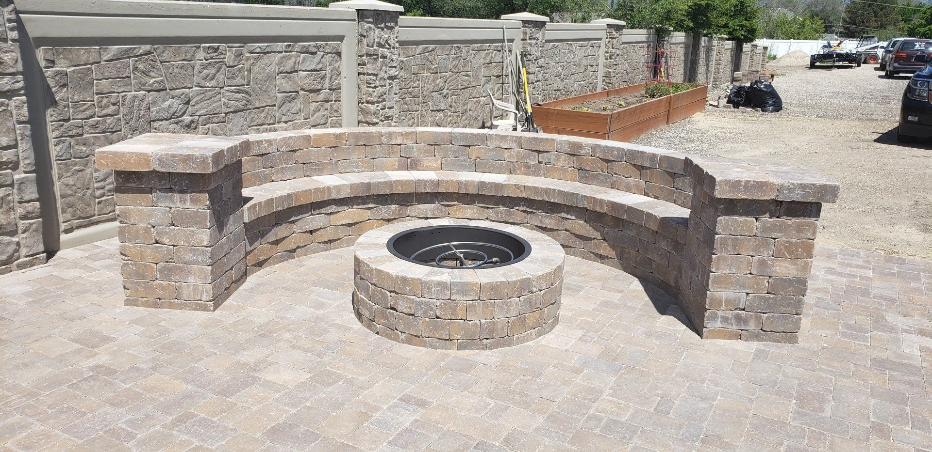 A fire pit is surrounded by a brick wall and a bench.