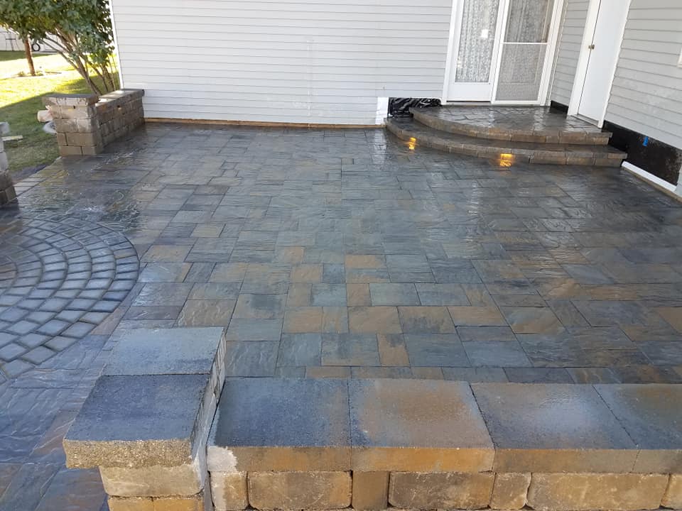 A patio with steps leading to the front door of a house.