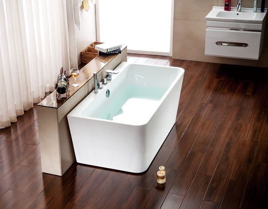 Baignoire blanche moderne remplie d'eau dans une salle de bains avec sol, comptoir et lavabo en bois foncé.