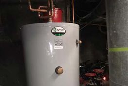 A. O. Smith water heater in a basement with copper pipes and a metal flue.