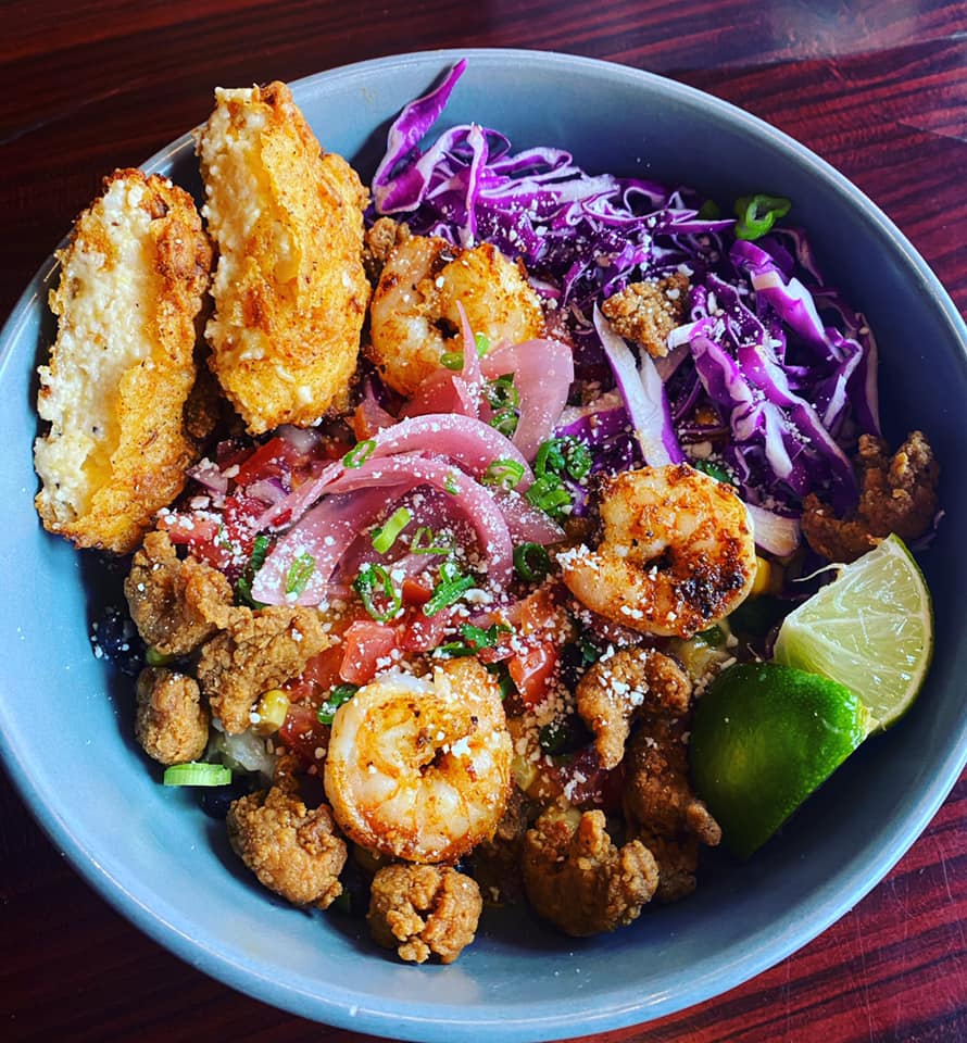 A bowl of food with shrimp and cabbage on a table