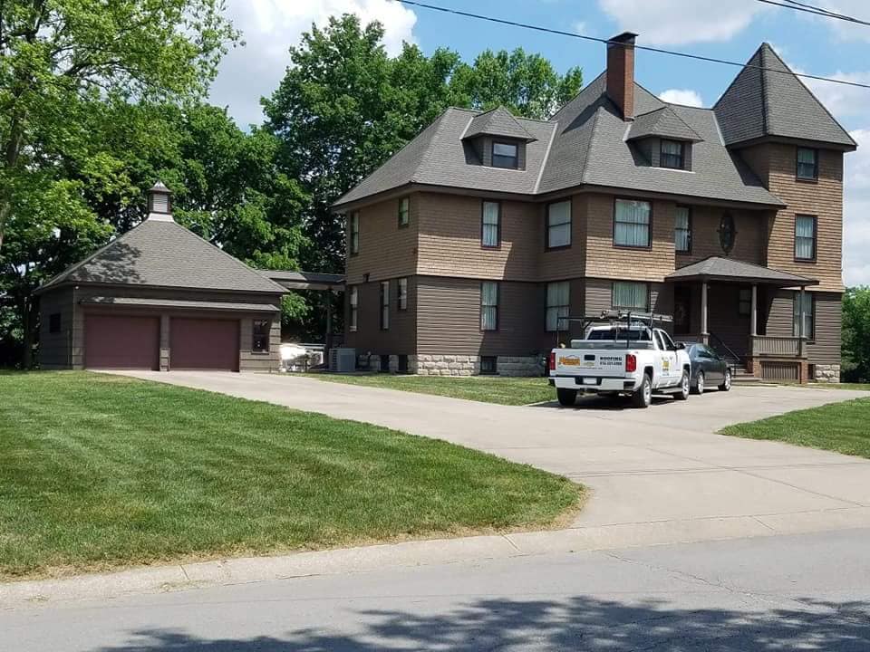 A white truck is parked in front of a large house.