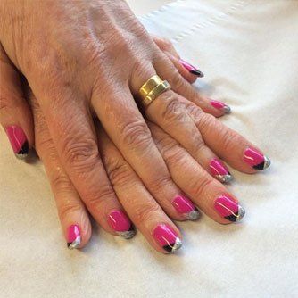 Hands with bright pink French manicure and a gold ring resting on a white surface