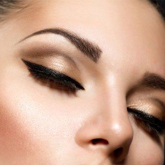 Close-up of a woman's closed eyes with bold black winged eyeliner and sculpted eyebrows