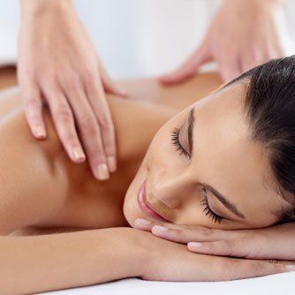 Woman receiving a relaxing massage while lying face down, eyes closed, in a spa setting