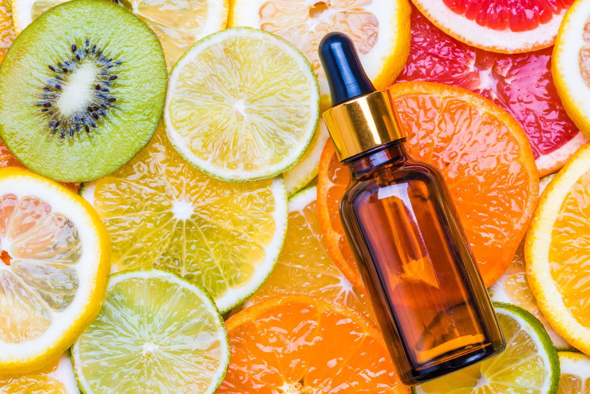 Eine Flasche Vitamin-C-Serum, umgeben von geschnittenen Zitrusfrüchten.