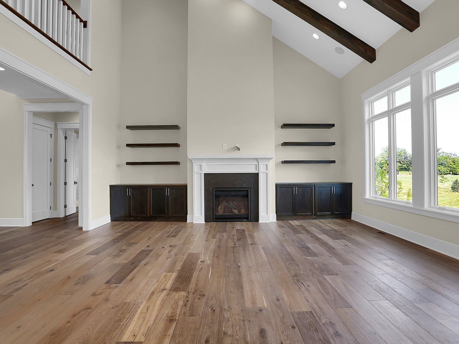 An empty living room with hardwood floors and a fireplace.