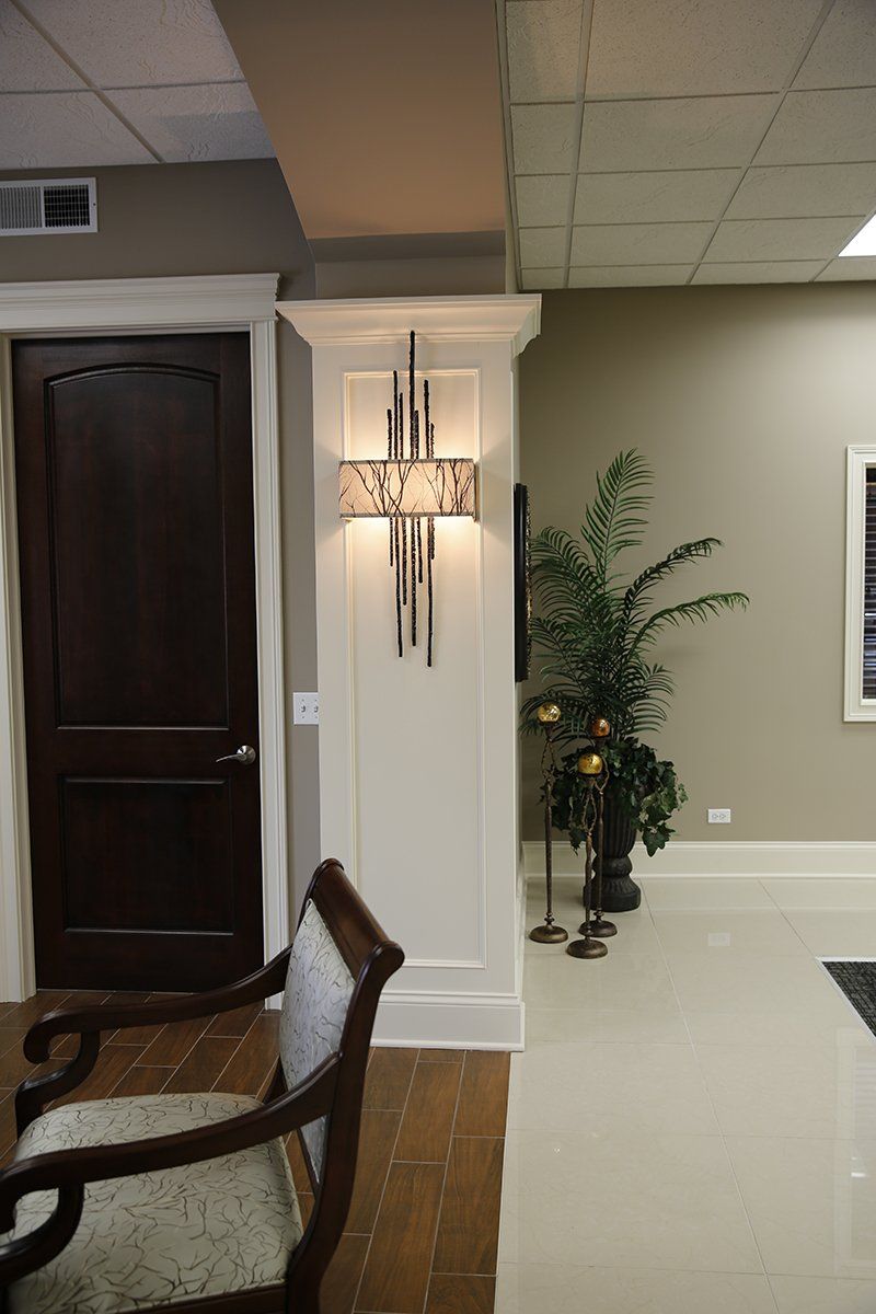 A dining room with a chair and a lamp on the wall.