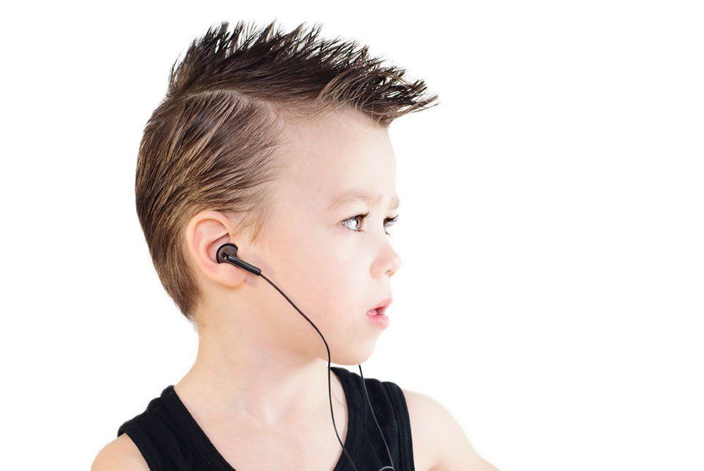 A young boy with a mohawk is wearing headphones.
