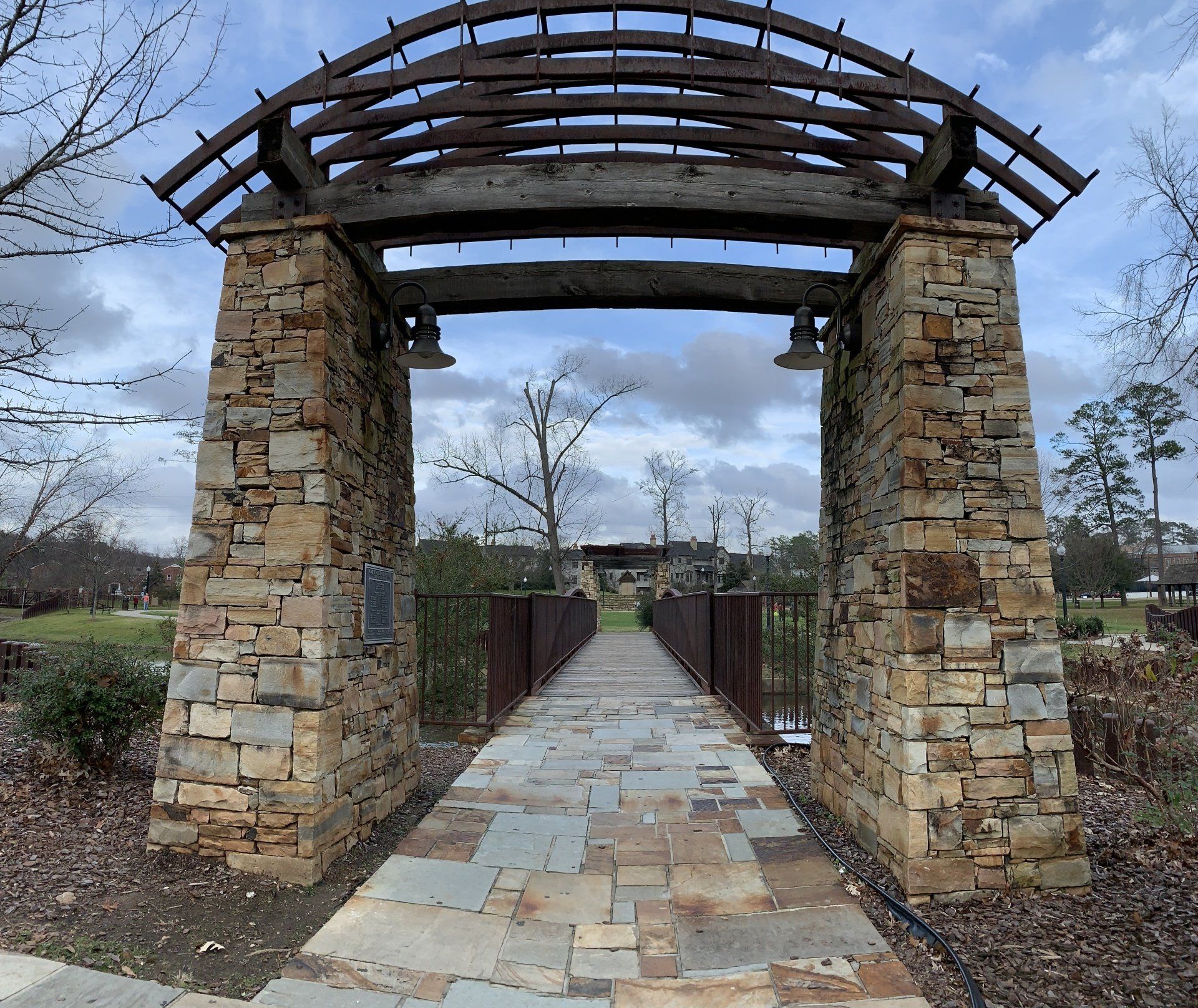 A stone archway leading to a bridge in a park