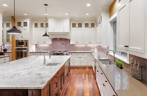 A kitchen with white cabinets , granite counter tops , and hardwood floors.