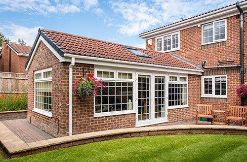 A brick house with a white roof and a patio in front of it.