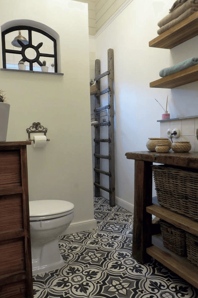 Badkamer met decoratieve vloertegels, houten planken en een rustieke ladder.