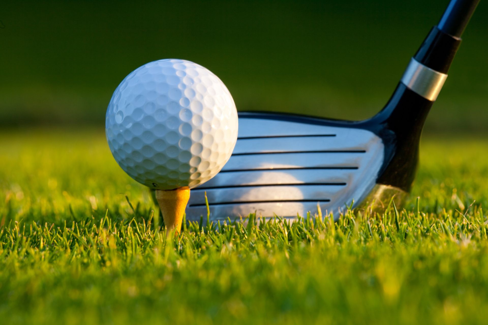 A golf ball is on a tee next to a golf club.