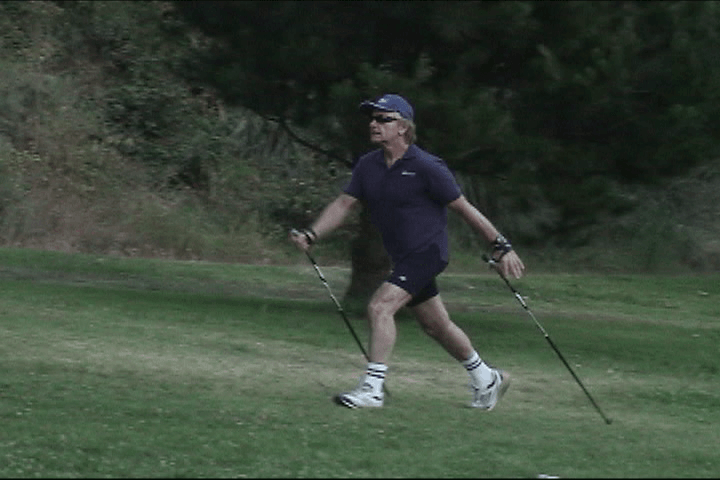 A man is walking on a golf course holding golf clubs