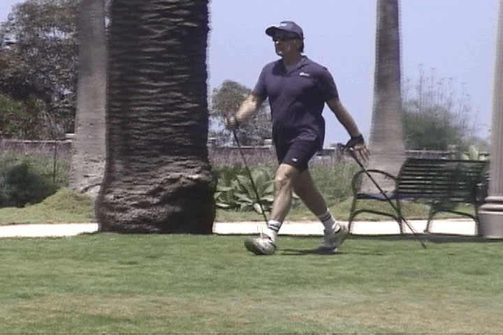 A man is walking in a park with a golf club