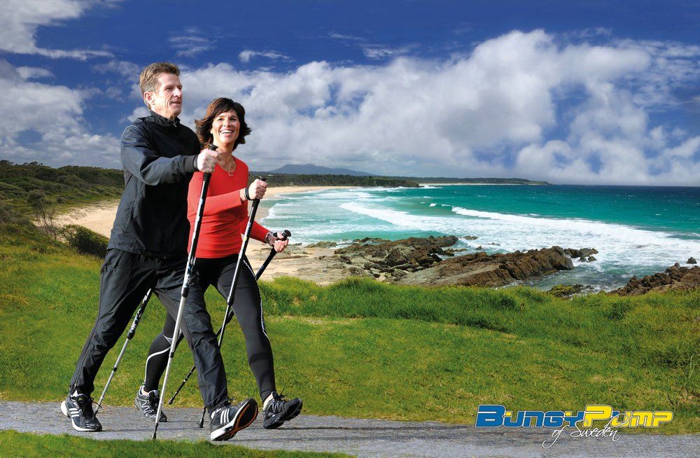 A man and a woman are walking on a path near the ocean.