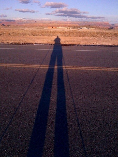 A shadow of a person standing on the side of a road