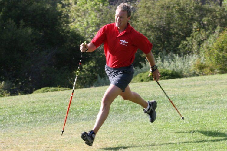 A man in a red shirt is running with walking poles