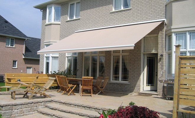 A house with a patio with a table and chairs under an awning