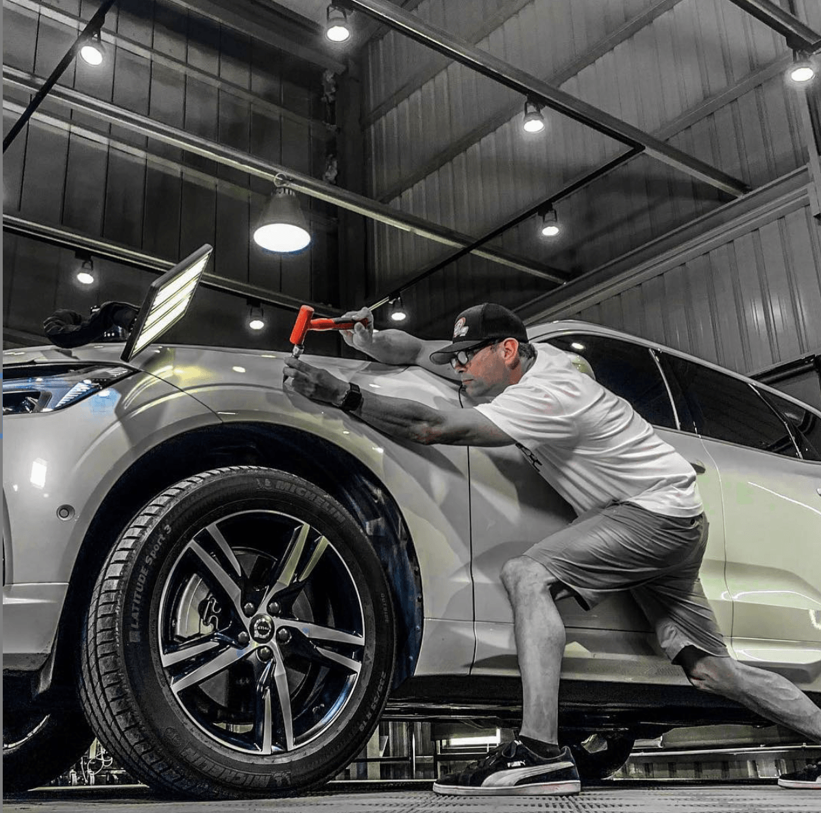 Technician repairing dent in a fender using paintless dent removal tools- shop service in Summerville Sc.