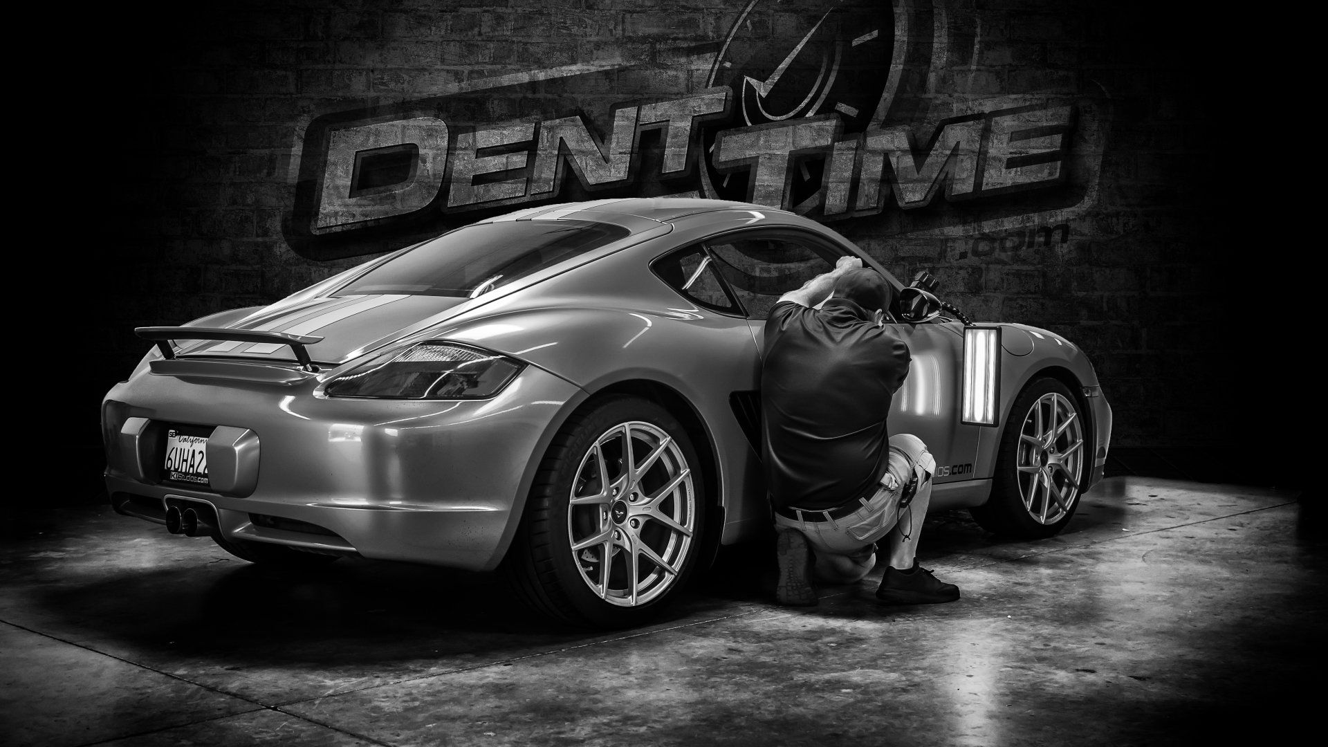 Technician performing paintless dent repair on a silver Porsche at Charleston Dent Company in Charleston, SC- expert PDR for sports cars and luxury vehicles.
