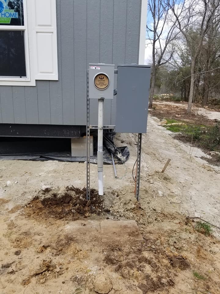 a meter box is sitting in the dirt in front of a house .