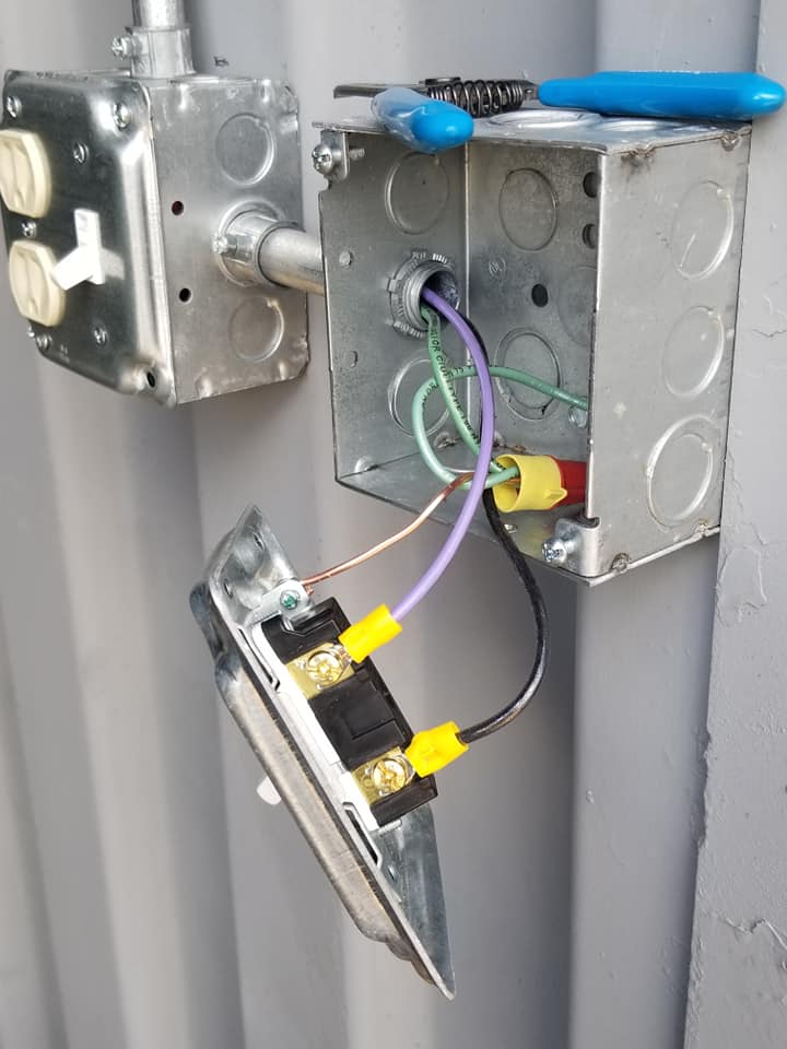 an electrical box with wires coming out of it and a pair of pliers .
