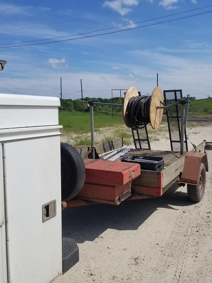 a trailer with a ladder on it is parked on a dirt road .