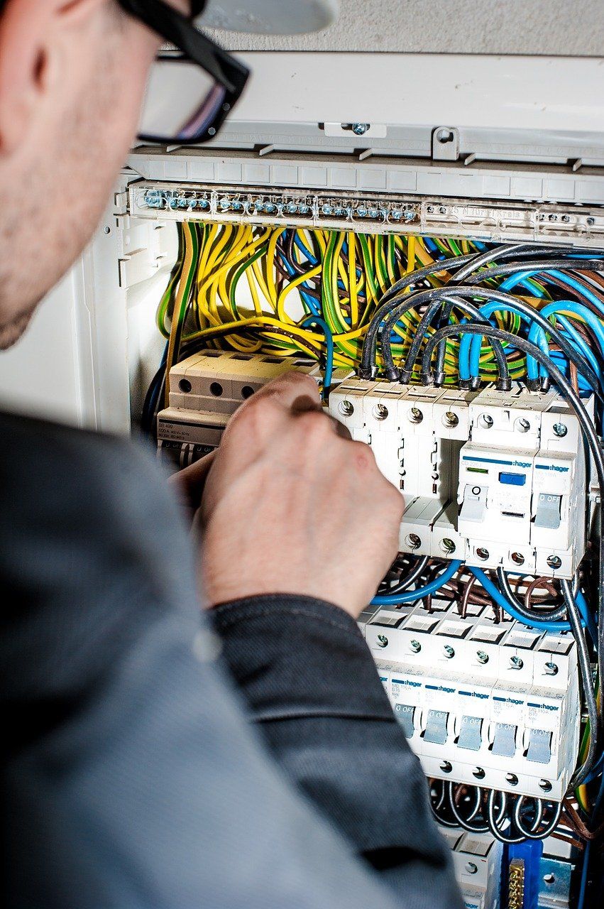 a man is working on an electrical box with a screwdriver .