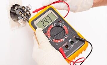 Electrician Checking Voltage in an Outlet — Electrical Services in Charlotte NC Electrician Checking Voltage in an Outlet — Electrical Services in Charlotte NC