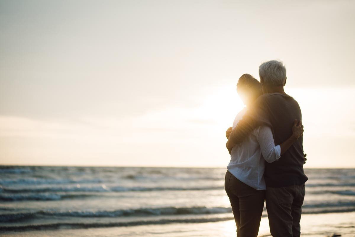 Ein Mann und eine Frau umarmen sich bei Sonnenuntergang am Strand.