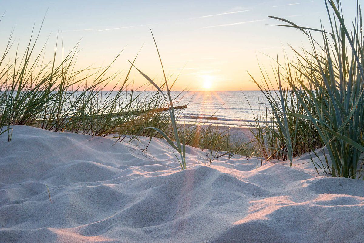 Ein Sandstrand mit einem Sonnenuntergang im Hintergrund