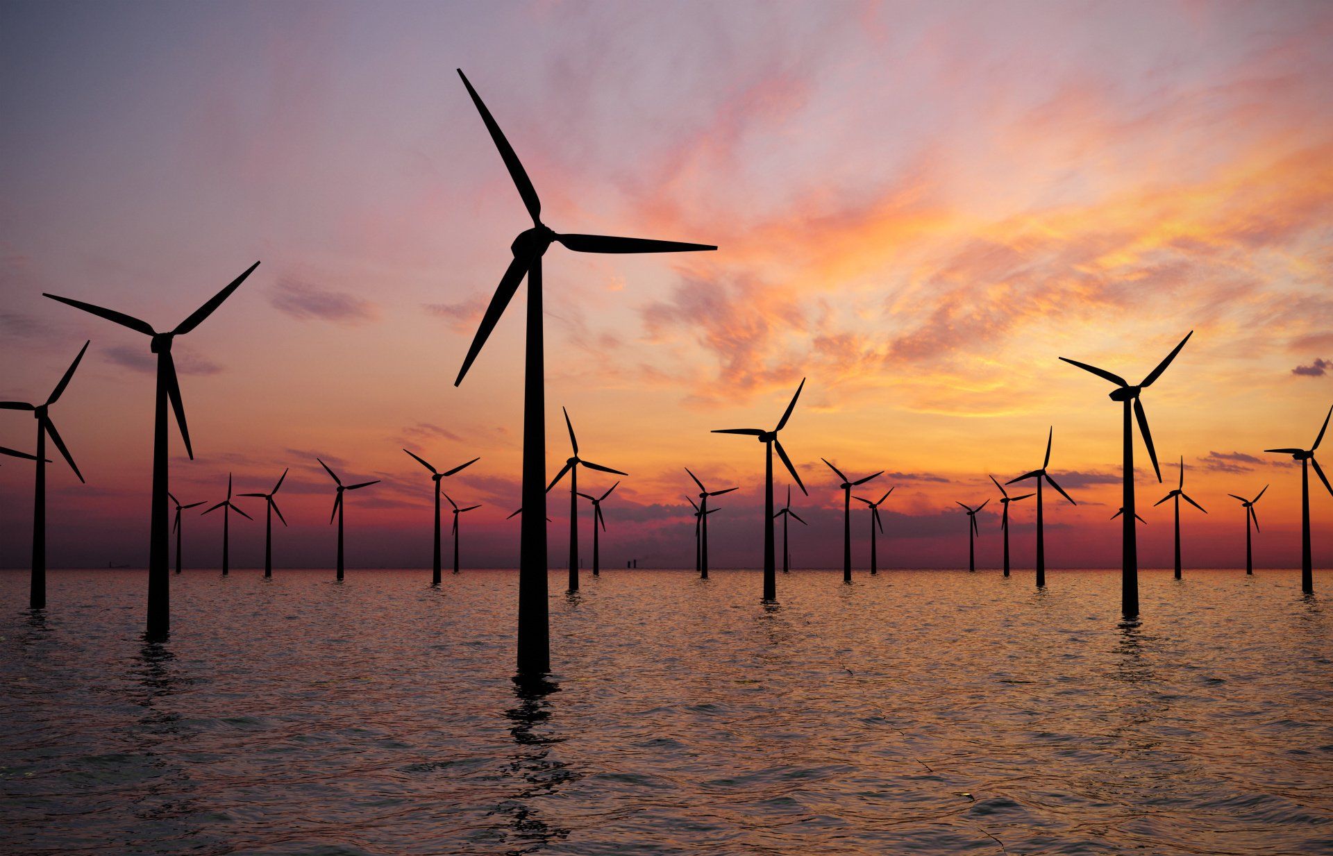 Windturbinen im Meer bei Sonnenuntergang mit orangefarbenem und violettem Himmel.