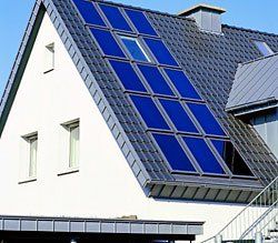Weißes Haus mit dunkelblauen Solarmodulen auf einem grauen Ziegeldach.