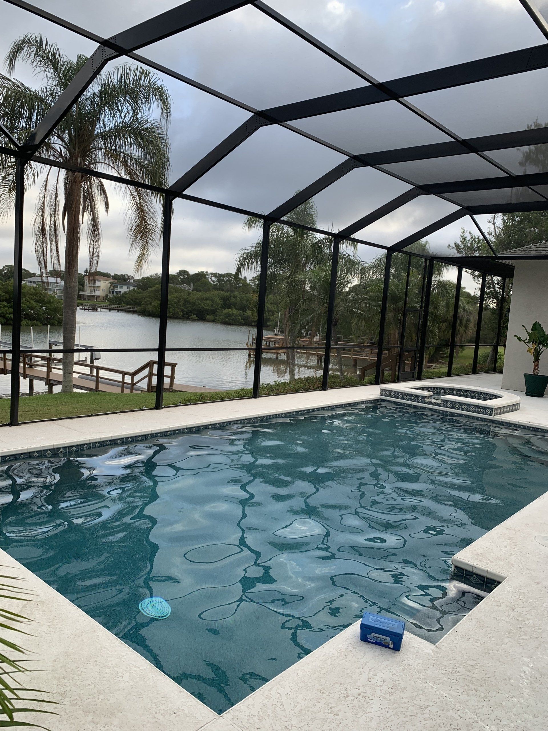 Screened-in backyard pool with blue water, white deck, and lake view beyond the patio.