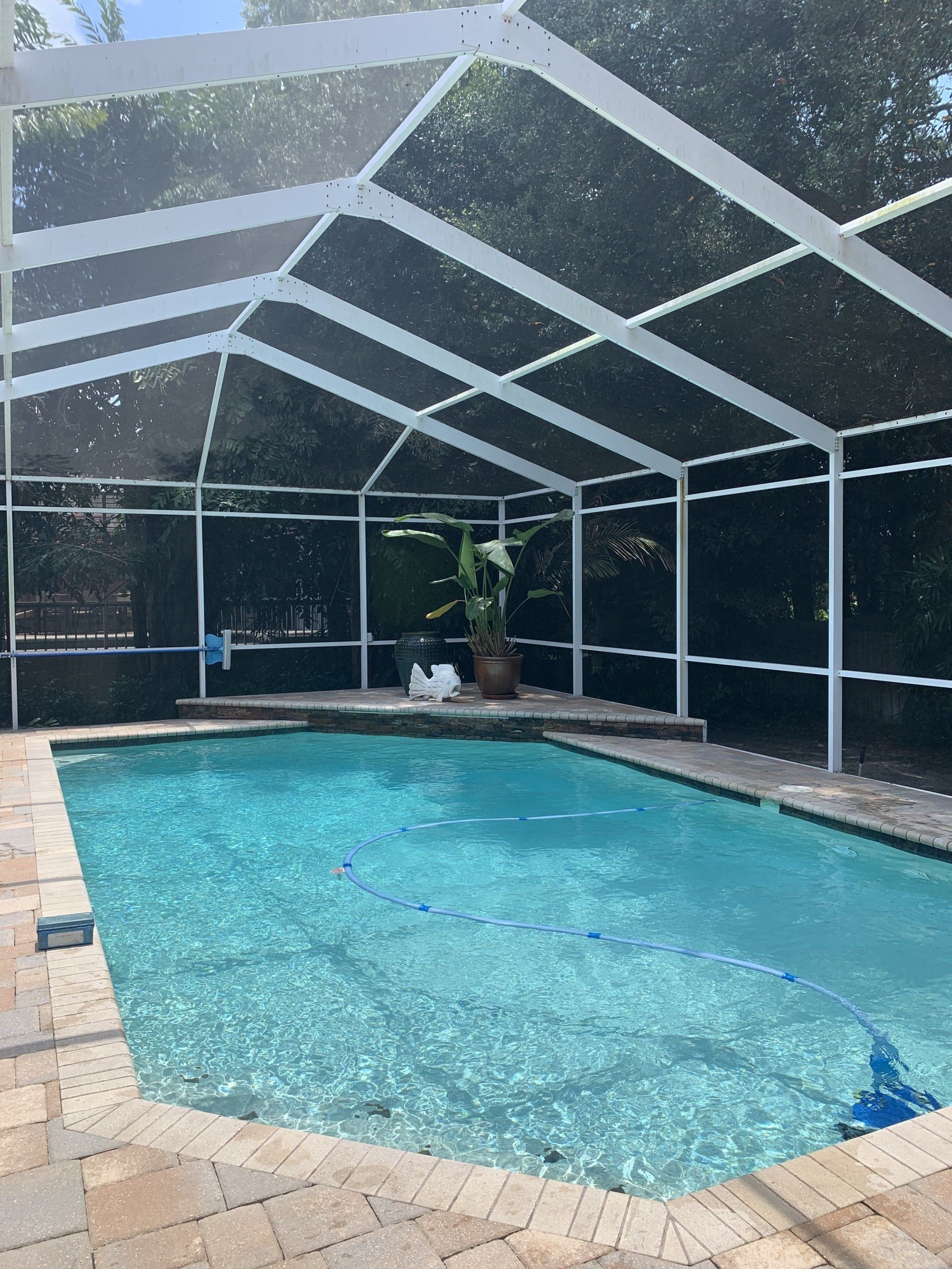 Indoor screened-in swimming pool with turquoise water and a tan tiled deck