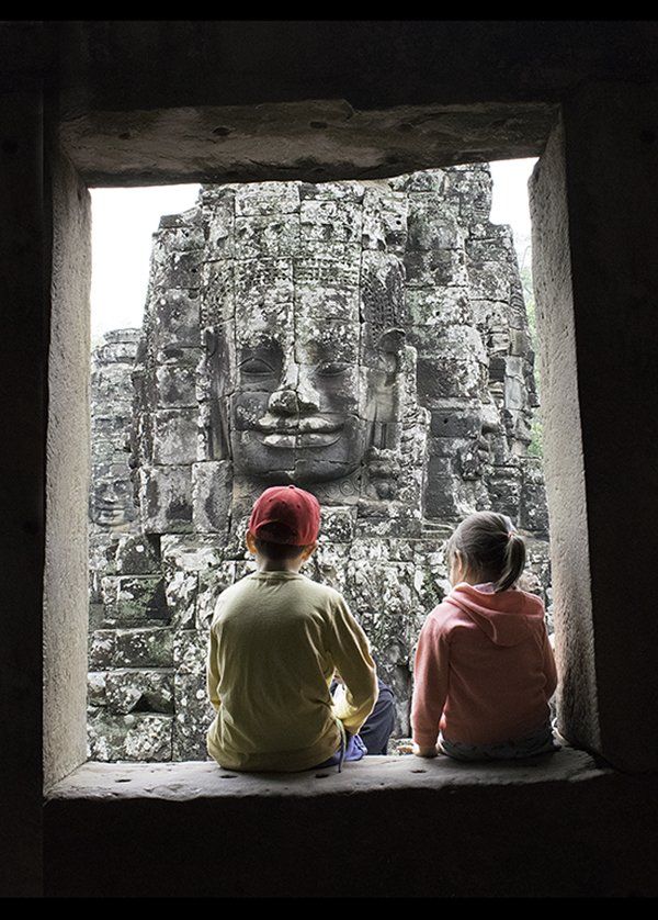 documentary photo of children gazing at the edifice of Bayon ruins in Cambodia.