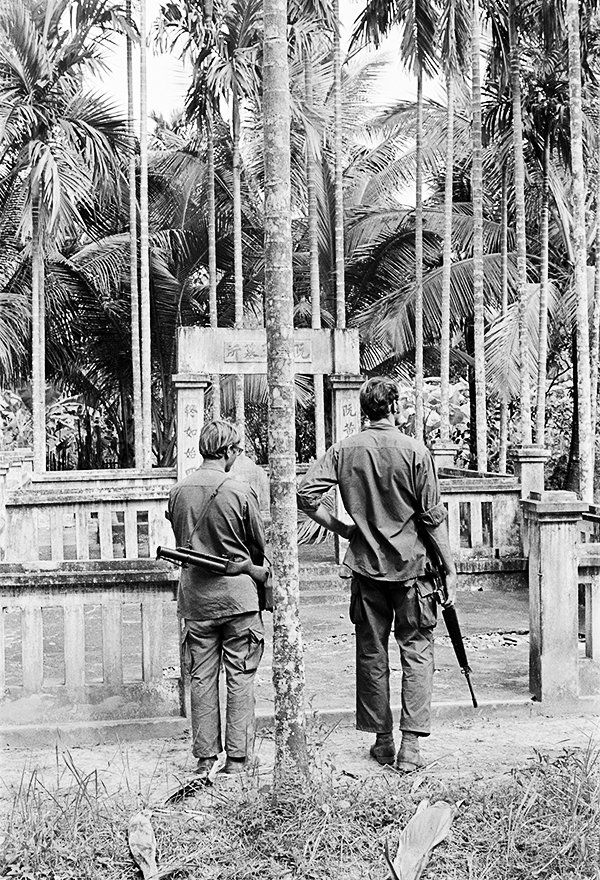 a documentary photograph of two soldiers in front of a Vietnamese shrine, 1971