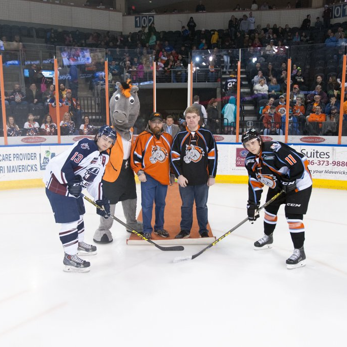 A group of hockey players are posing for a picture on the ice