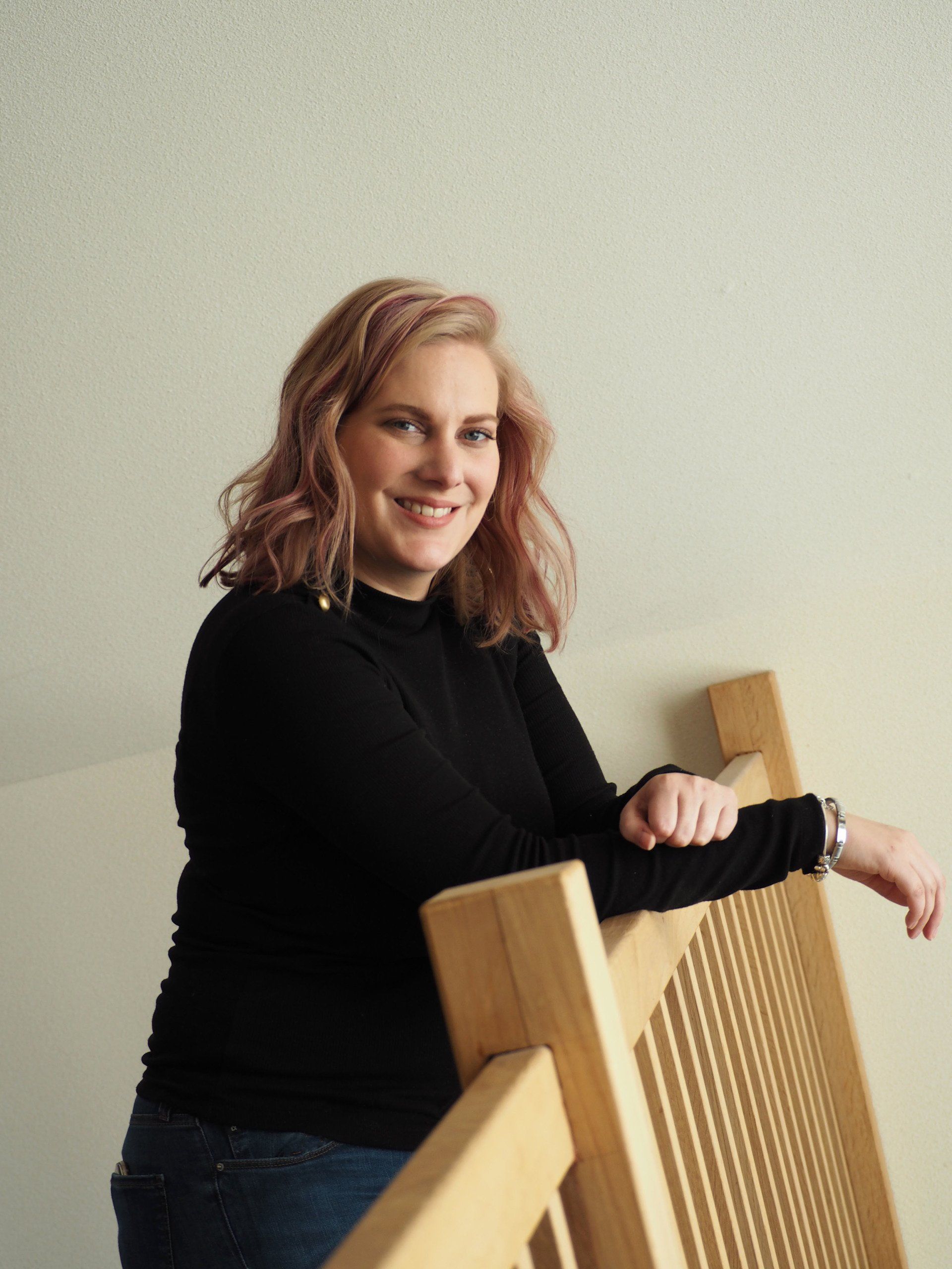 Een vrouw in een zwart shirt leunt op een houten reling