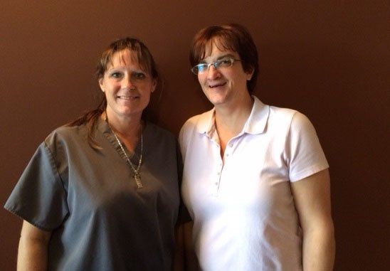 Two women are standing next to each other and smiling for the camera.