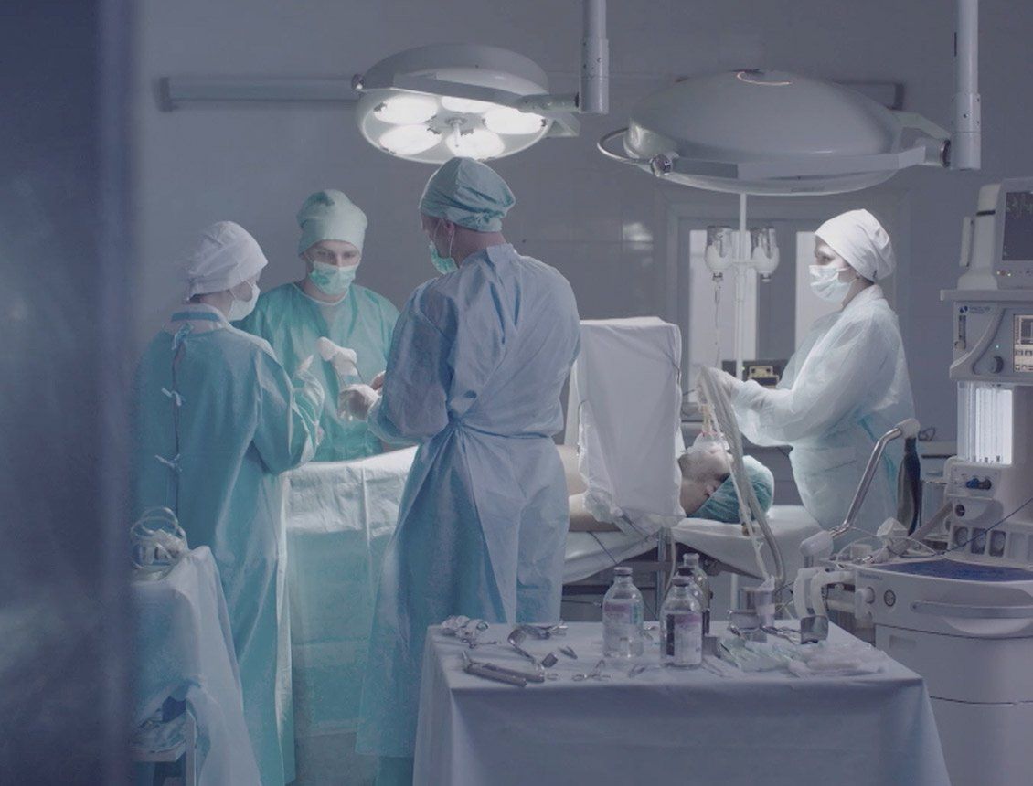 A group of surgeons are operating on a patient in an operating room.