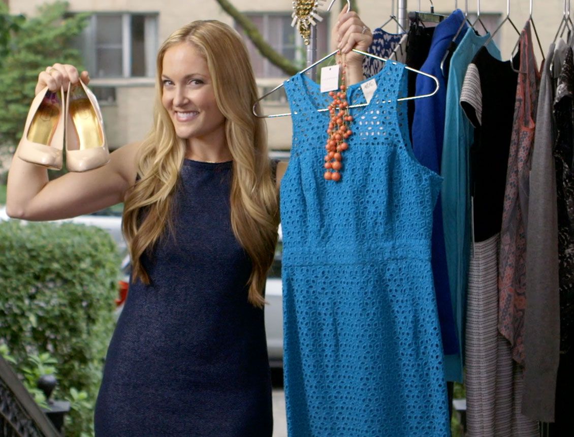 A woman is holding a pair of shoes and a blue dress